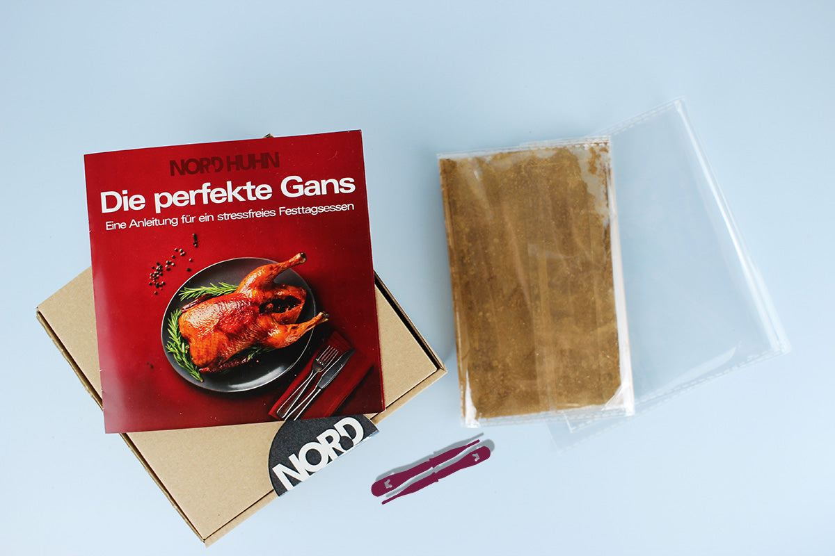 Anleitung 'Die perfekte Gans' mit einem Bild eines gebratenen Gänsebratens auf rotem Hintergrund, daneben Gewürzmischung in Plastikverpackung und zwei rote Verschlüsse auf hellblauem Untergrund