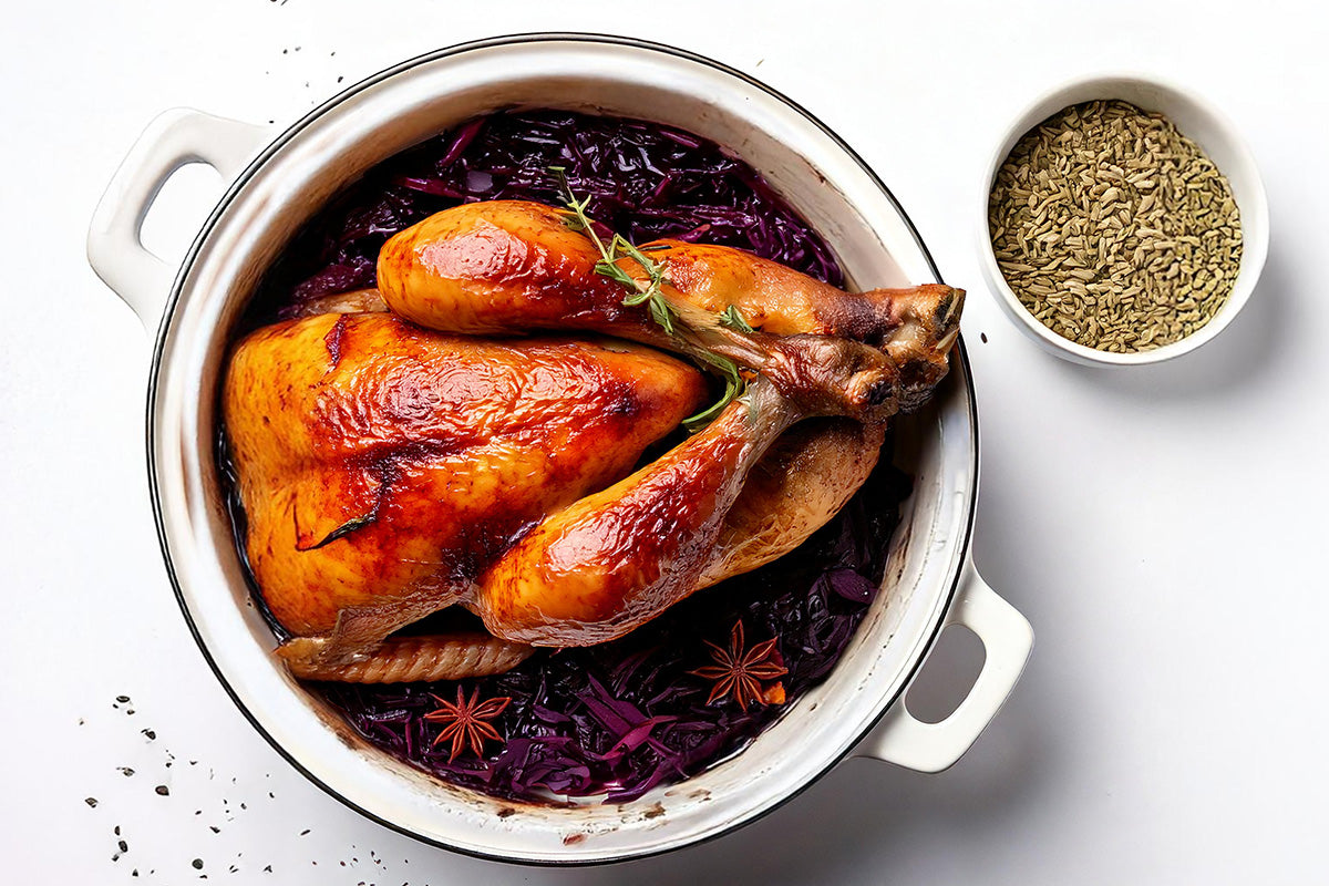 Knusprig gebratenes Perlhuhn in einem weißen Topf auf Rotkohl mit Sternanis, daneben eine Schale mit Fenchelsamen