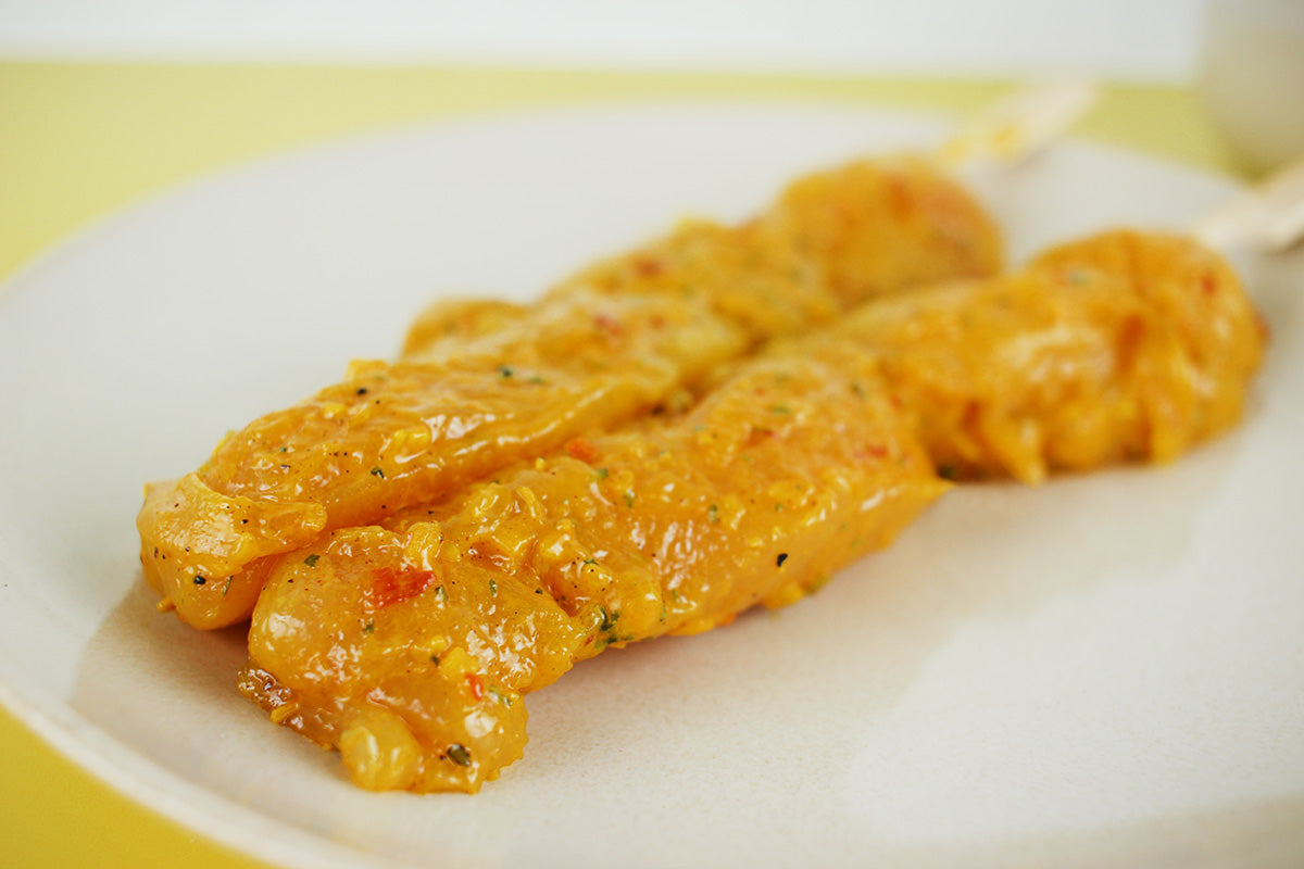 Zwei Curry-marinierten Grillspieße mit Gewürzen auf einem weißen Teller