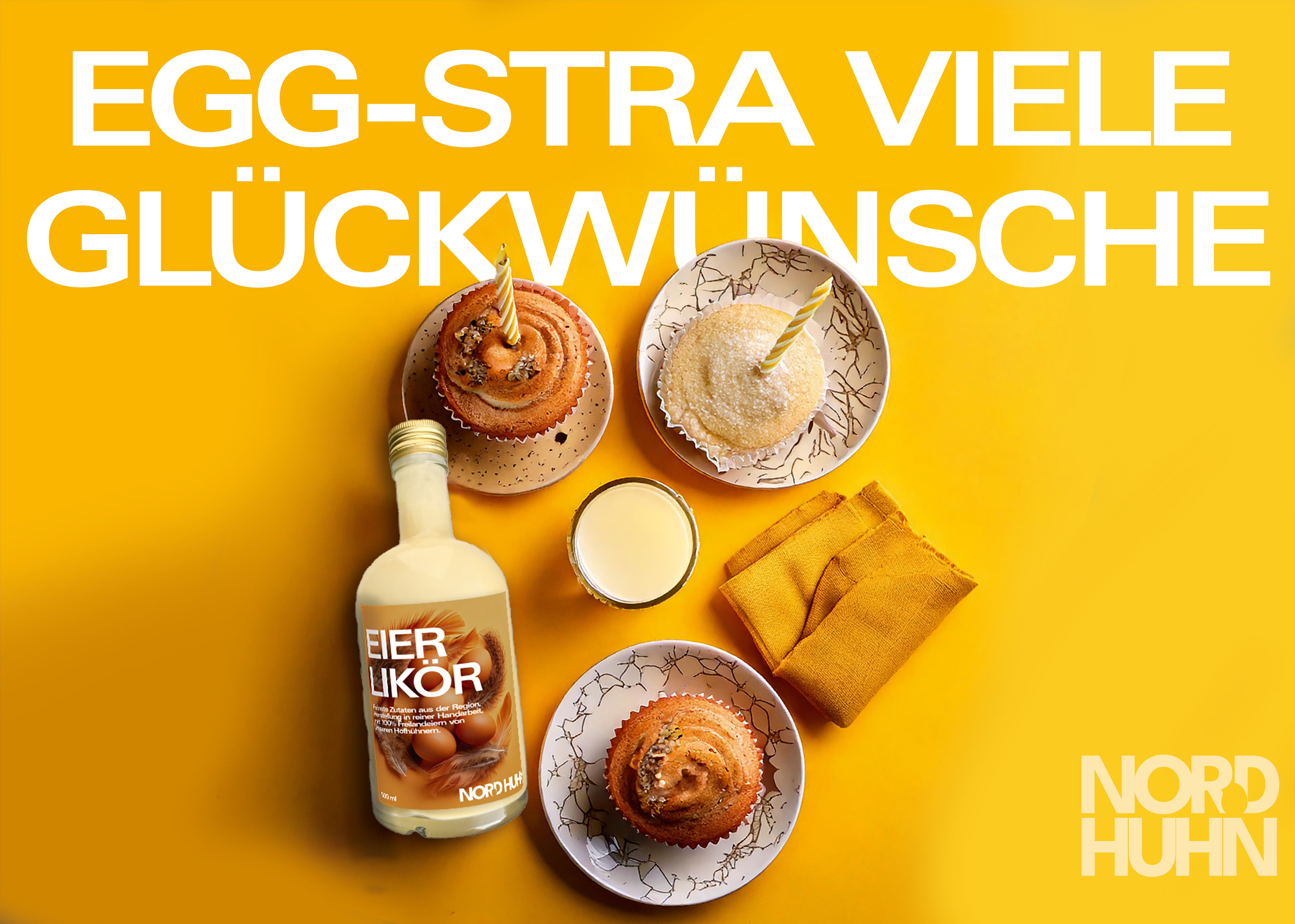 Flasche Eierlikör der Marke Nordhuhn neben drei Muffins mit je einer Kerze auf gelbem Hintergrund, Text 'EGG-STRA VIELE GLÜCKWÜNSCHE'