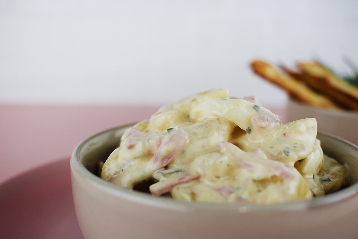 Kartoffelsalat mit Geflügelfleischwurst in cremiger Sauce in einer grauen Schüssel