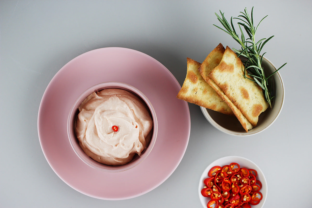 Schale mit cremigem Dip, daneben Schälchen mit Fladenbrot und Rosmarinzweig, kleine Schale mit roten Chiliringeln