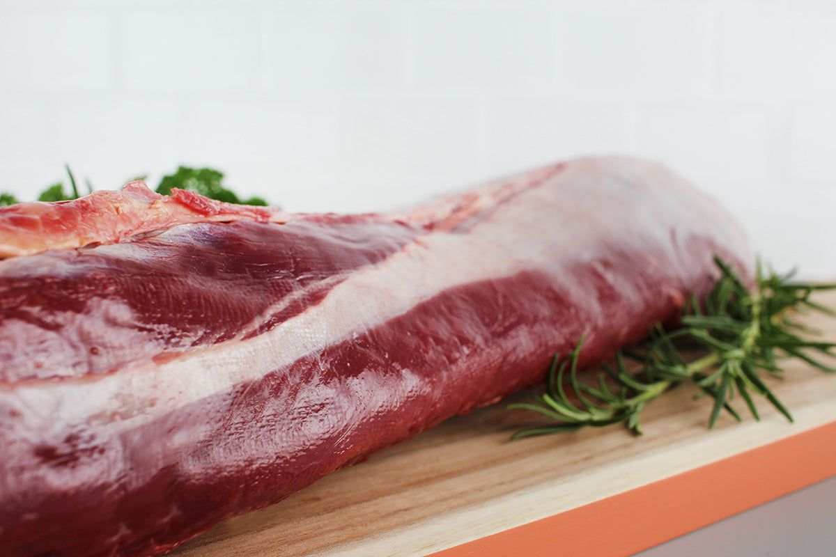 Roher Rehrücken auf Holzbrett mit Rosmarinzweigen