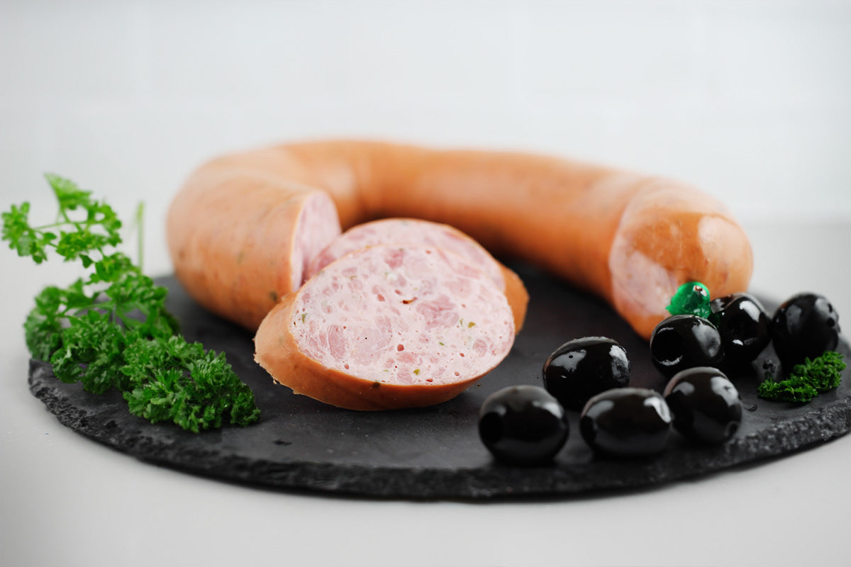 Ringförmige Geflügelkrakauer mit einer Scheibe, serviert auf Schieferplatte mit schwarzen Oliven und Petersilienzweigen